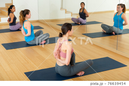 Women practicing yoga position pashchima namaskarasana 76639454