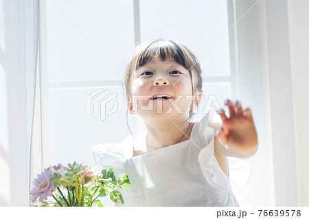 窓辺で花を持つ女の子 76639578