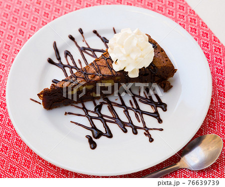 Tasty brownie cake served with butter cream and dark chocolate at plate 76639739