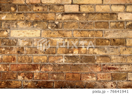 Aged partially crumbled brown brick wall background 76641941