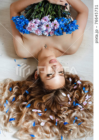 Gorgeous naked woman covering breast with flowers. 76645731