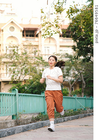 Healthy woman are running in the park in the morning. She smiled and enjoyed. 76649581