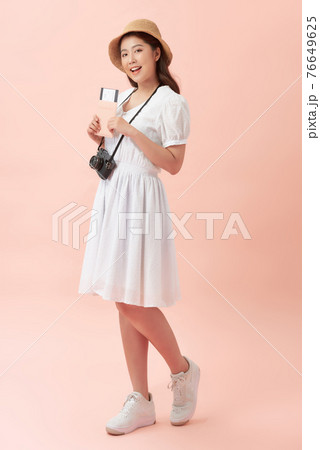 Smiling young beautiful Asian tourist woman holding passport isolated on pink studio background 76649625