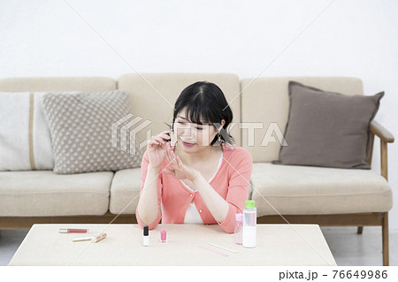 部屋でマニュキュアを塗る若い女性 76649986