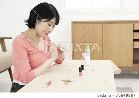 部屋で爪やすりで爪のケアをする若い女性 部屋で爪やすりで爪のケアをする若い女性 76649987