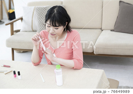 部屋で爪やすりで爪のケアをする若い女性 部屋で爪やすりで爪のケアをする若い女性 76649989