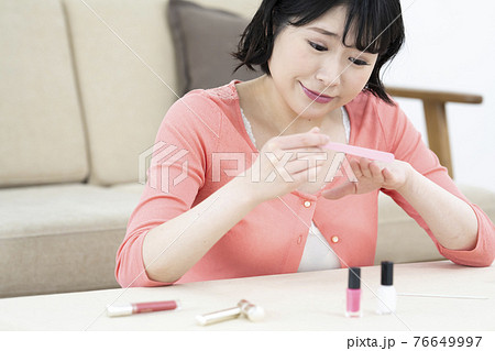 部屋で爪やすりで爪のケアをする若い女性 部屋で爪やすりで爪のケアをする若い女性 76649997