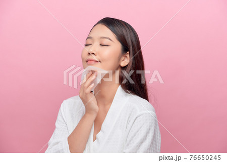 Face skin care. Smiling woman using facial oil blotting paper portrait. 76650245