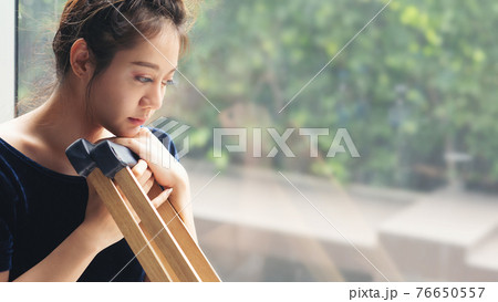 Young woman with broken leg at window 76650557