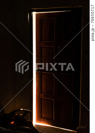 bright warm light leaking from an opened door 76650717