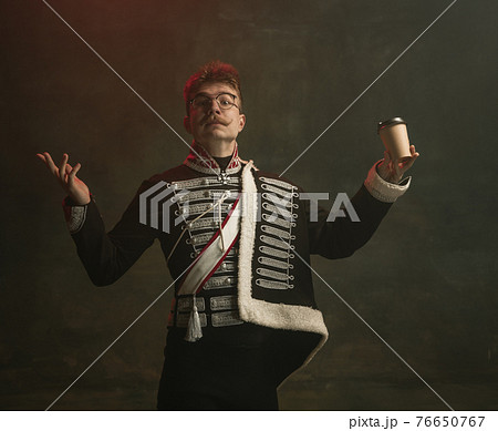 Young man in suit as royal person isolated on dark green background. Retro style, comparison of eras concept. Beautiful male model like historical character, monarch, old-fashioned. 76650767