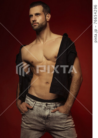 Muscle strong face beautiful stripped male model in casual look with denim on bordo red isolated font background 76654296