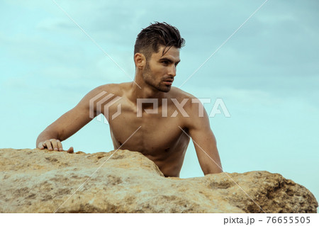 Sexy beautiful striped male model on the nature background with sand and sky on the beach on the sunset Sexy beautiful striped male model on the nature background with sand and sky on the beach on the sunset 76655505