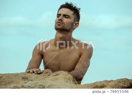 Sexy beautiful striped male model on the nature background with sand and sky on the beach on the sunset 76655506