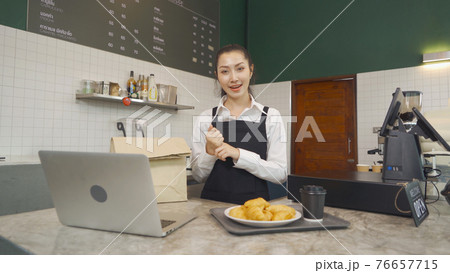Portrait of Asian woman barista people in apron selling products online via live e-commerce live or conference sales social media, cafe restaurant cashier. waitress in coffee shop. People lifestyle. Portrait of Asian woman barista people in apron selling products online via live e-commerce live or conference sales social media, cafe restaurant cashier. waitress in coffee shop. People lifestyle. 76657715