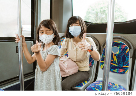 a woman with a thumbs up and a little girl with a hand gesture symbolizes love when wearing a mask 76659184