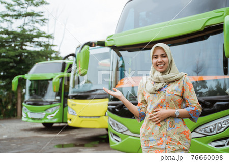 a veiled female bus crew smiling with hand gestures offering something a veiled female bus crew smiling with hand gestures offering something 76660098