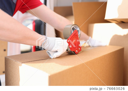 Man seals box with adhesive tape dispenser 76663026