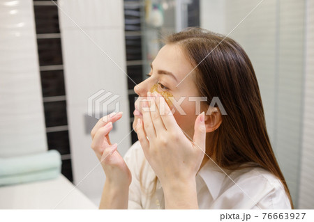 Caucasian woman applying hydrogel patches on under eye area, looking at mirror. Happy young lady enjoying morning anti age anti wrinkle routine in bathroom Caucasian woman applying hydrogel patches on under eye area, looking at mirror. Happy young lady enjoying morning anti age anti wrinkle routine in bathroom 76663927