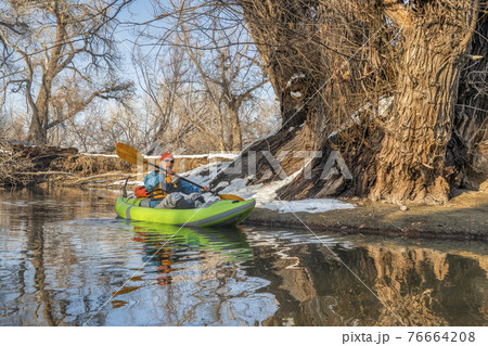 paddling inflatable whitewater kayak on a river in winter 76664208