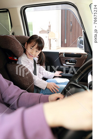 助手席に取り付けたジュニアシートに座る女の子 76675234