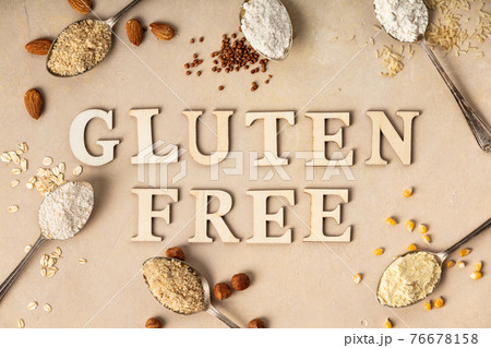 Metal spoons of various gluten free flour almond, oatmeal, buckwheat, rice, corn and gluten free lettering made of wooden letters, flat lay, top view 76678158