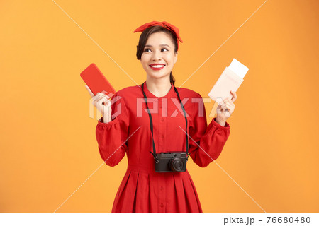 Happy woman tourist travel holding camera and passport isolated on yellow background, asian 76680480