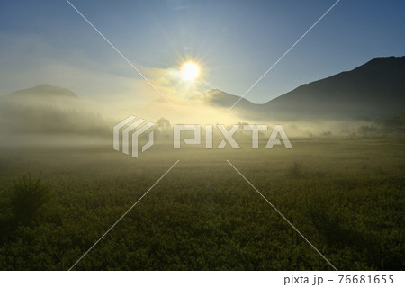 霧の小田代ヶ原と奥日光の山々に日の出の写真素材