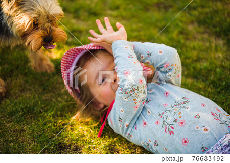 Baby girl lying on grass with dog in backyard on summer day. Baby girl lying on grass with dog in backyard on summer day. 76683492