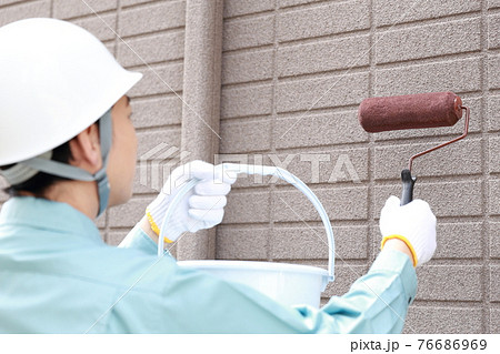 一軒家の外壁に塗装をする作業員の男性 一軒家の外壁に塗装をする作業員の男性 76686969
