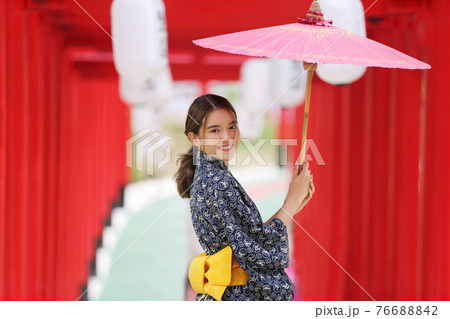 woman in kimono holding umbrella walking into at the shrine red gate, in Japanese garden. woman in kimono holding umbrella walking into at the shrine red gate, in Japanese garden. 76688842