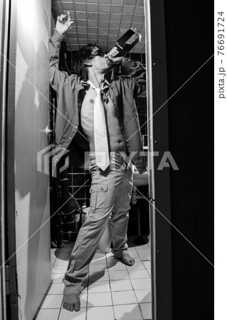 Drunk Man is standing in a toilet with a bottle of whiskey Drunk Man is standing in a toilet with a bottle of whiskey 76691724