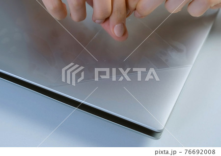 A woman's hand removes the film from a new laptop, closeup view. 76692008