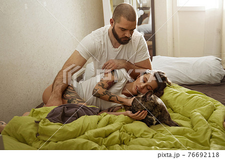 Stroking dog while laying on the bed in modern apartments 76692118