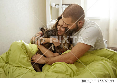 Family of two with a dog having fun together at home, while laying at the bed Family of two with a dog having fun together at home, while laying at the bed 76692144