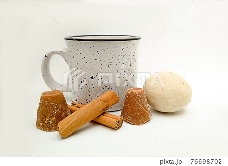 cup of atole, also known as atol, (traditional drink based on hot corn and Mesoamerican dough) and ingredients for its preparation cinnamon, dough, brown sugar 76698702
