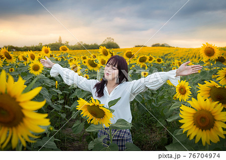 Happy enjoy summer girl in sunflower field in spring. Asian young woman joyful and smiling at sunset time Happy enjoy summer girl in sunflower field in spring. Asian young woman joyful and smiling at sunset time 76704974