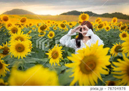 Happy enjoy summer girl in sunflower field in spring. Asian young woman joyful and smiling at sunset time Happy enjoy summer girl in sunflower field in spring. Asian young woman joyful and smiling at sunset time 76704976