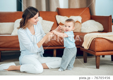 Mom sitting on floor and standing baby 76705456