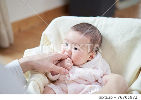 パパの指を食べるアジア人の赤ちゃんの写真素材