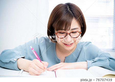 リビングで勉強をする眼鏡の若い女性 76707439