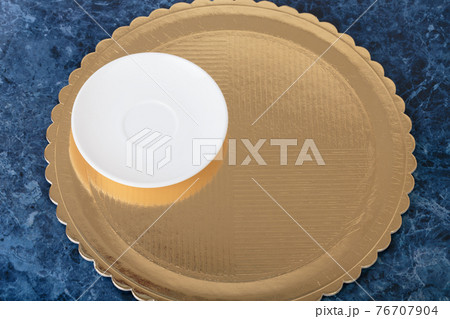 Golden disposable cake tray and porcelain saucer. 76707904
