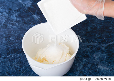 Sugar is poured into the cream cheese. Sugar is poured into the cream cheese. 76707916