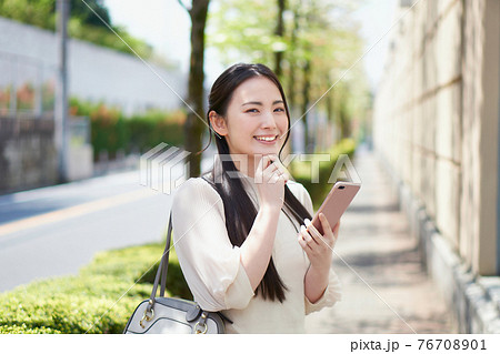 キャンパス前でスマホを持つ大学生 76708901