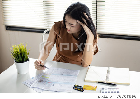 Young Asian woman is stressed and overthink by debt from many credit cards and bills. 76708996