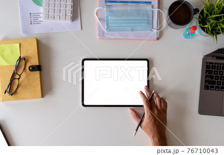 White office desk table with surgical face mask and sanitizer bottle or alcohol gel with calculator isolated on white background, Hand of man using tablet with blank screen at home 76710043