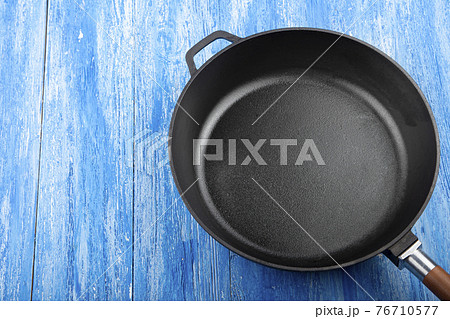 Empty cast iron pan on wooden culinary background, space for text. Empty cast iron pan on wooden culinary background, space for text. 76710577