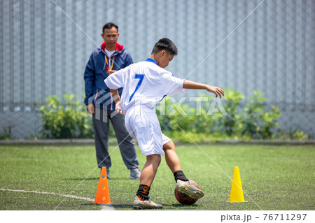 Football soccer training for kids. Coach explaining the game plan. Young boys improving soccer skills local Thailand 76711297