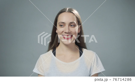 Photo of young smiling woman on grey Photo of young smiling woman on grey 76714286