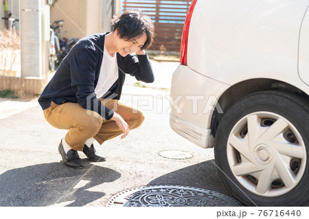 車に傷をつけて落ち込む男性 車に傷をつけて落ち込む男性 76716440